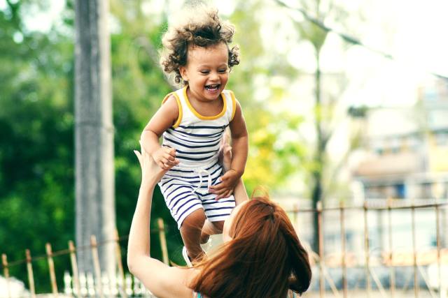 Red haired mother lifting a curly haired mixed child. Start supporting your kids against racism at an early age.