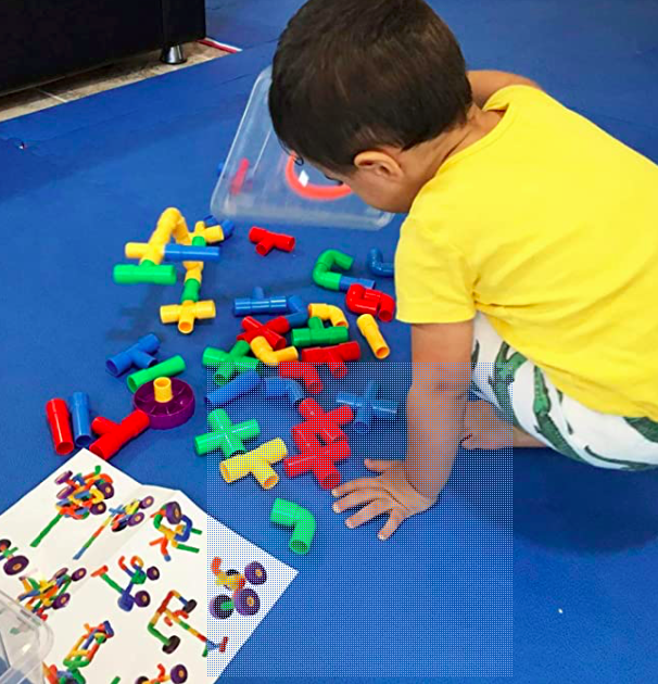 Preschool child playing with construction toy. This is an engaging STEM activity that will promote intellectual growth.